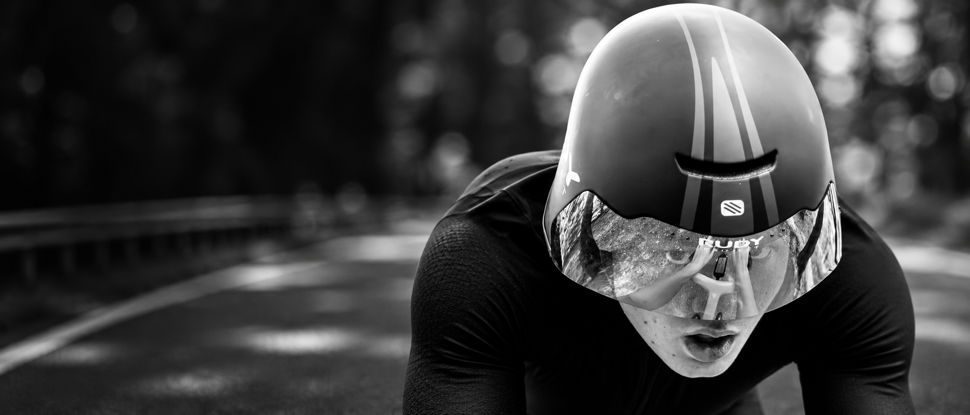 Black and white portrait of a cyclist in a time-trial helmet, expanded into a cinematic race scene.